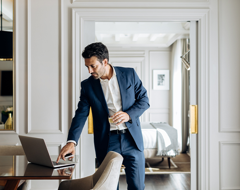 Business professional checking his laptop on dining table within luxury home