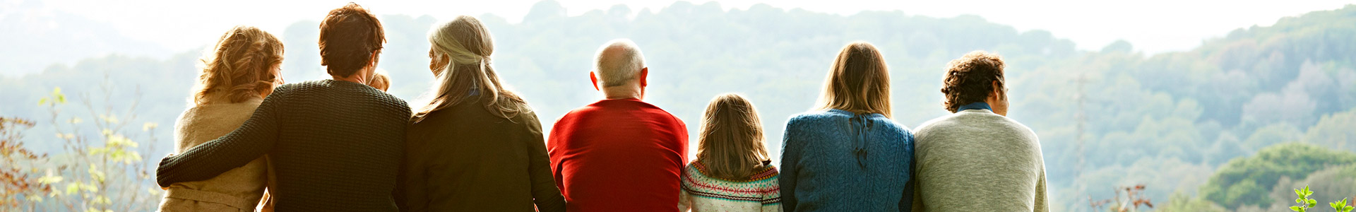 Row of different generations of the same family sitting on a log