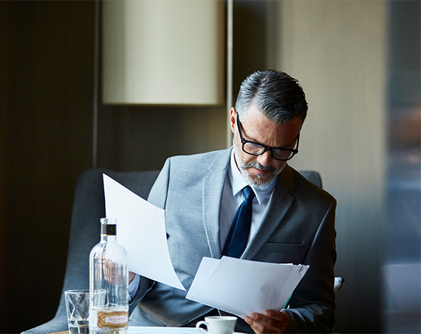Broker looking through paperwork while drinking a coffee