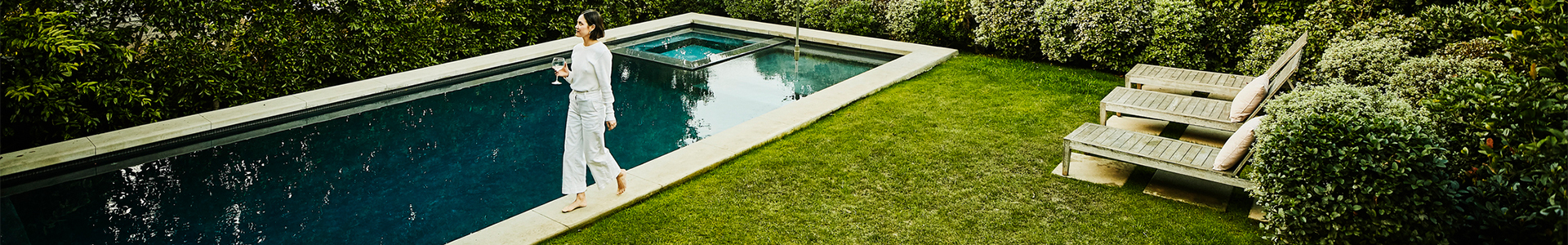 female walking around her back garden with outdoor swimming pool