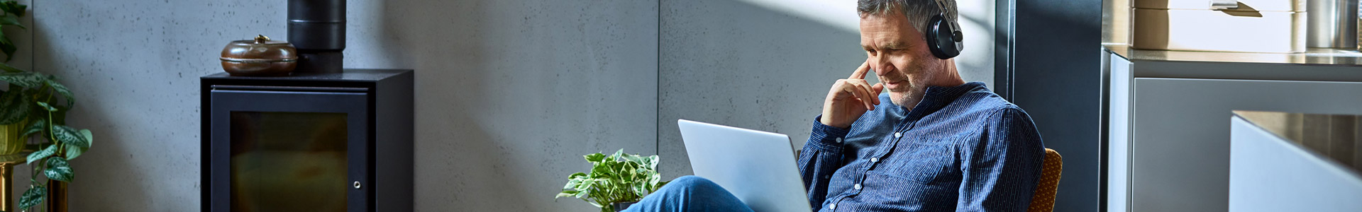 Male sitting in lounge with laptop and earphones