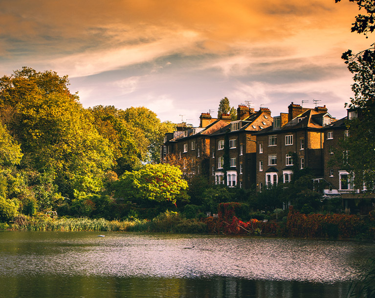 Row of houses by river side with leaves changing colour on the trees