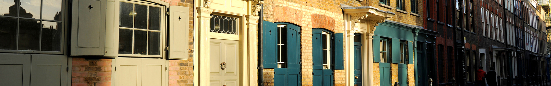 Looking down a street of terraced houses with shutters on windows