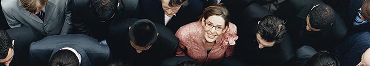Businesswoman Looking up at Camera and Standing Outdoors Surrounded by a Large Group of Business People