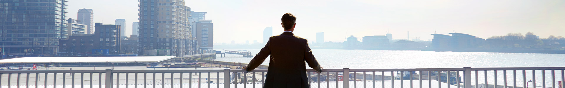 Business man standing on bridge looking out over river
