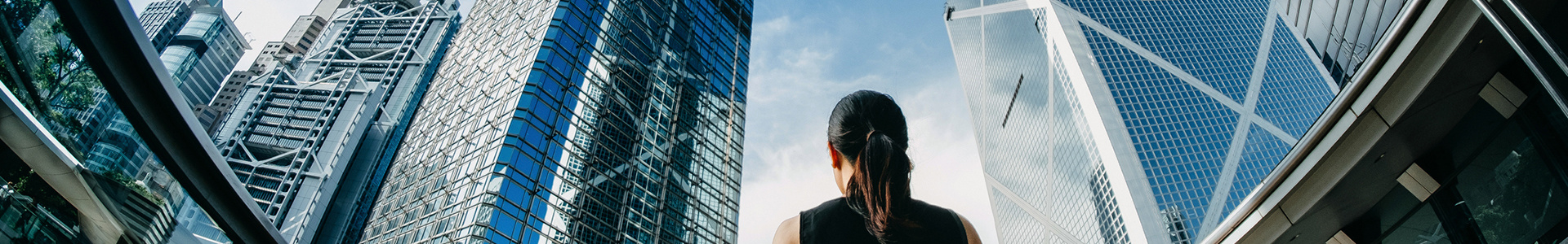 Business woman looking up at office buildings