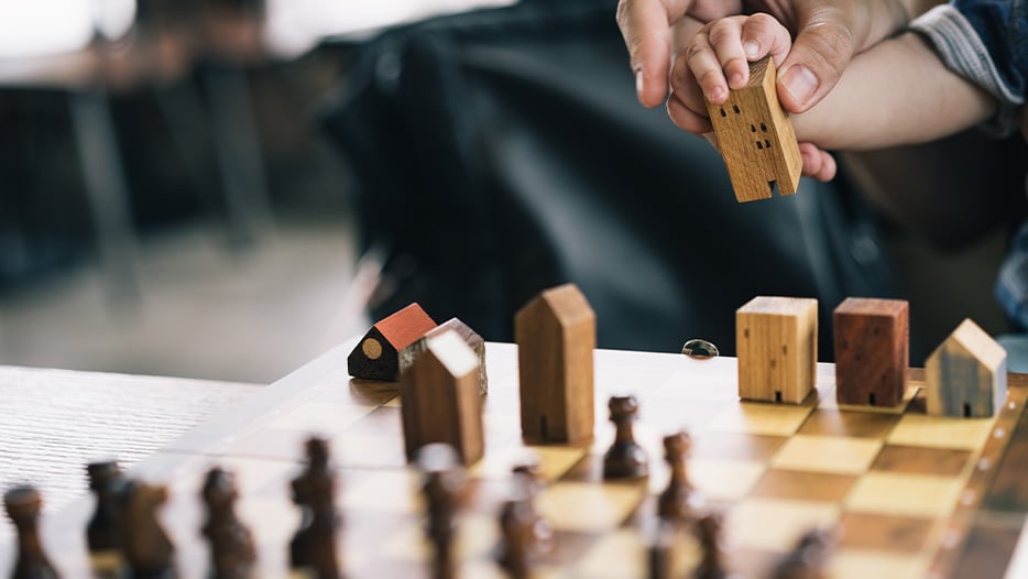 Dad teaching son to play chess with set showing houses