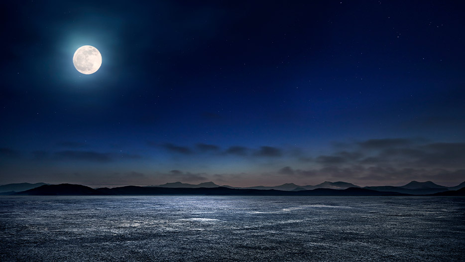 Full moon casting light over the ocean at night