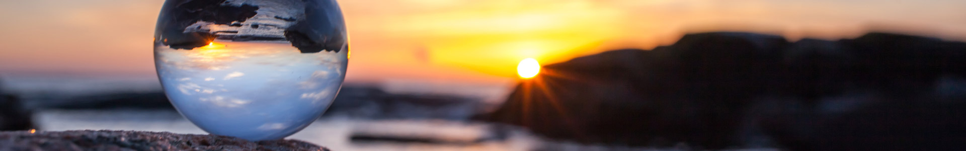Cystal ball sitting on top of a rock by the sea with sunset