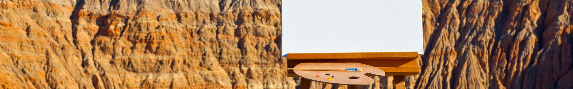 Painting easel and paints infront a scenic backdrop of mountains