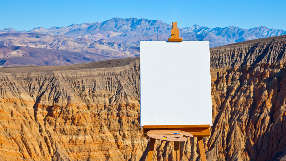 Painting easel and paints infront a scenic backdrop of mountains