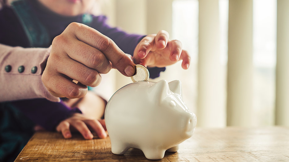 Parent and child putting coin in money box
