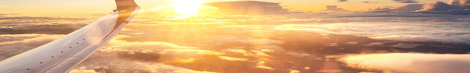 Plane wing amogst the clouds with sunset shining on plane