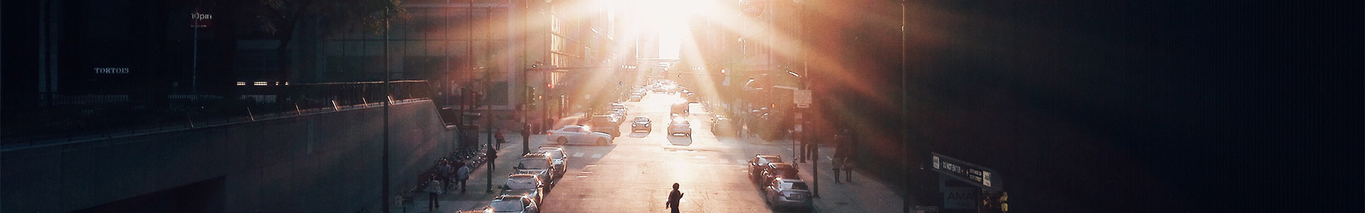 Sunlight breaking through down a city street with buildings either side