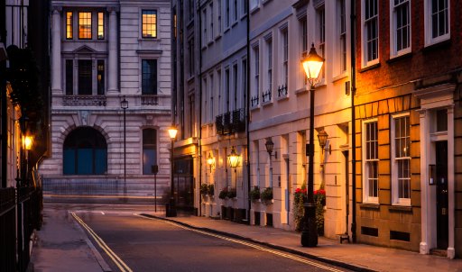 Old british inner city houses lit by street lamps at dusk