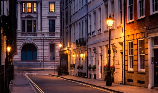 Old british inner city houses lit by street lamps at dusk