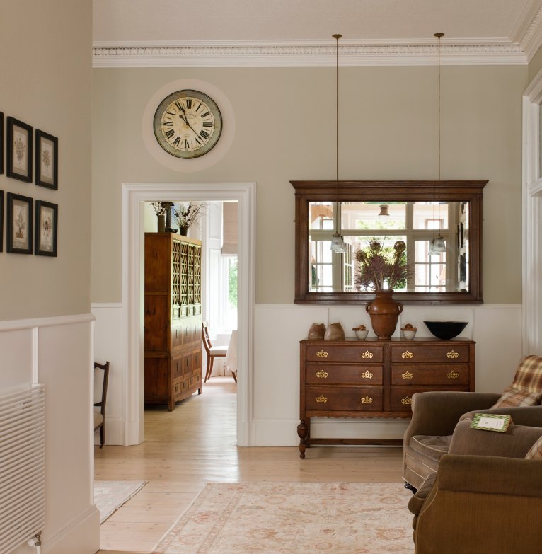 The hallway of a luxury house featuring photo frames on the wall and leather armchairs