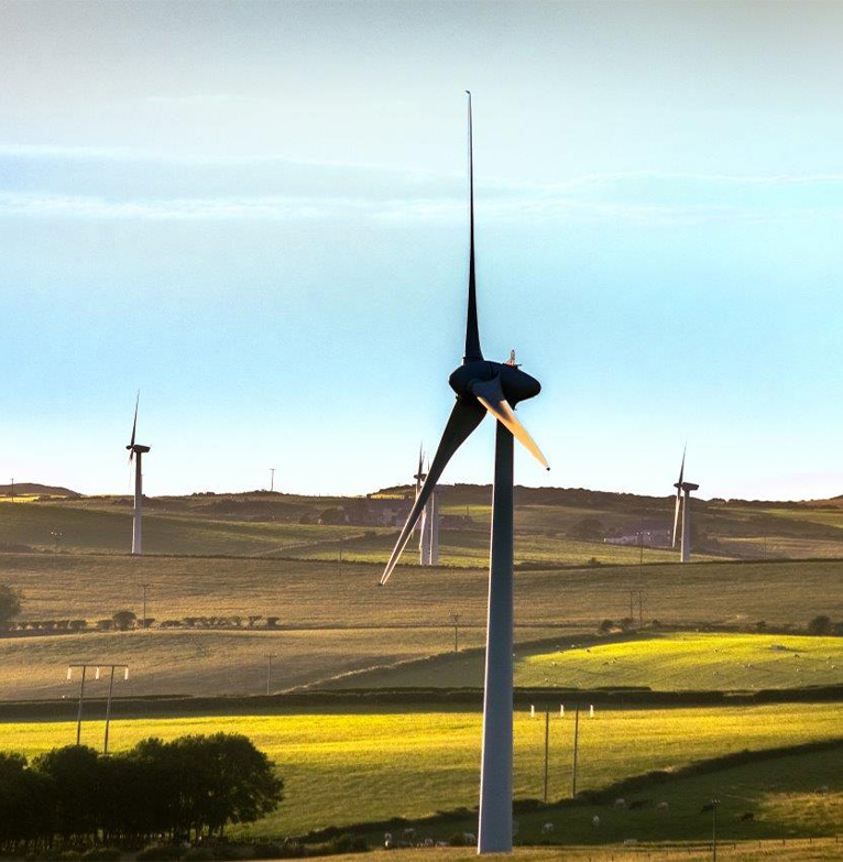 Looking across wind turbines spinning in green fields