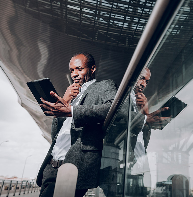 Business man checking his tablet while waiting outside an airport