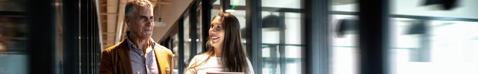A woman and man conversing while walking through an office