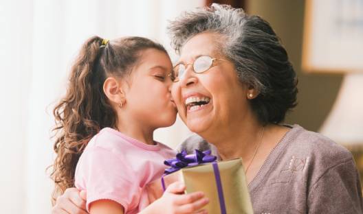 A grandmother gets a kiss on the cheek from her granddaughter after giving her a present