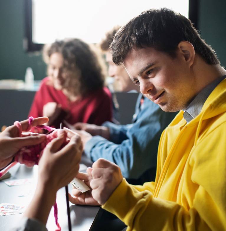 A boy is taught how to knit