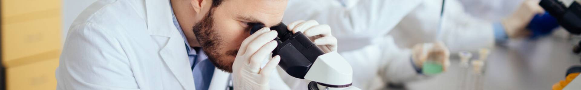 A medical researcher peers into a microscope in a laboratory