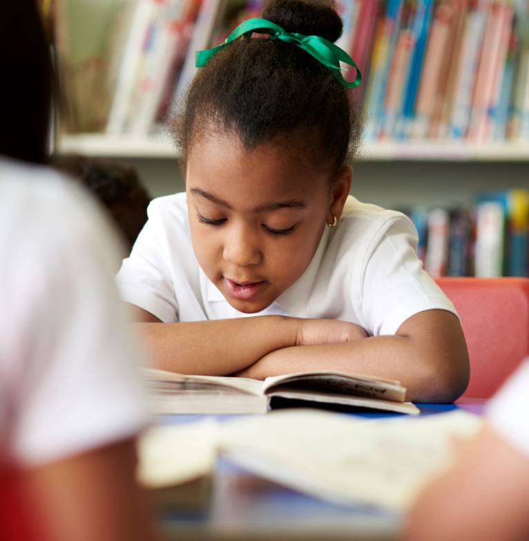 A young girl reads a book in a library