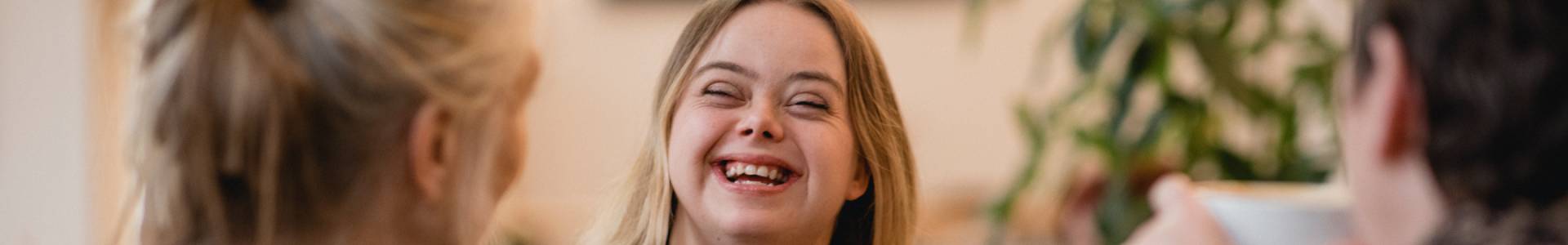 A young lady wearing headphones grins at the person she speaks to