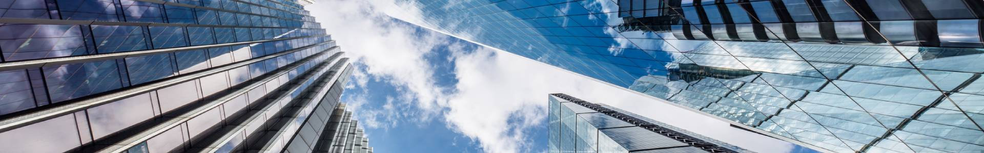 Looking up towards the sky through glassy corporate skyscrappers in the city