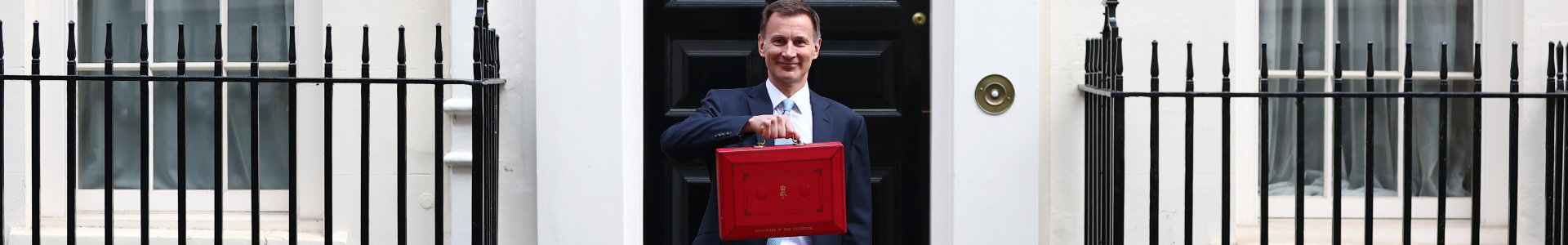 The Chancellor of the Exchequer holds the red budget box aloft outside number 11 Downing Street