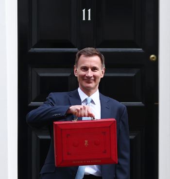 The Chancellor of the Exchequer holds the red budget box aloft outside number 11 Downing Street