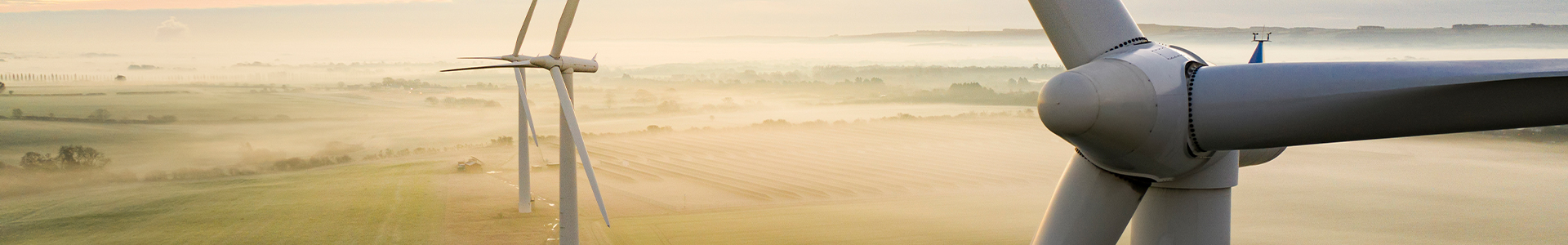 Wind turbines against a sun rise with fog