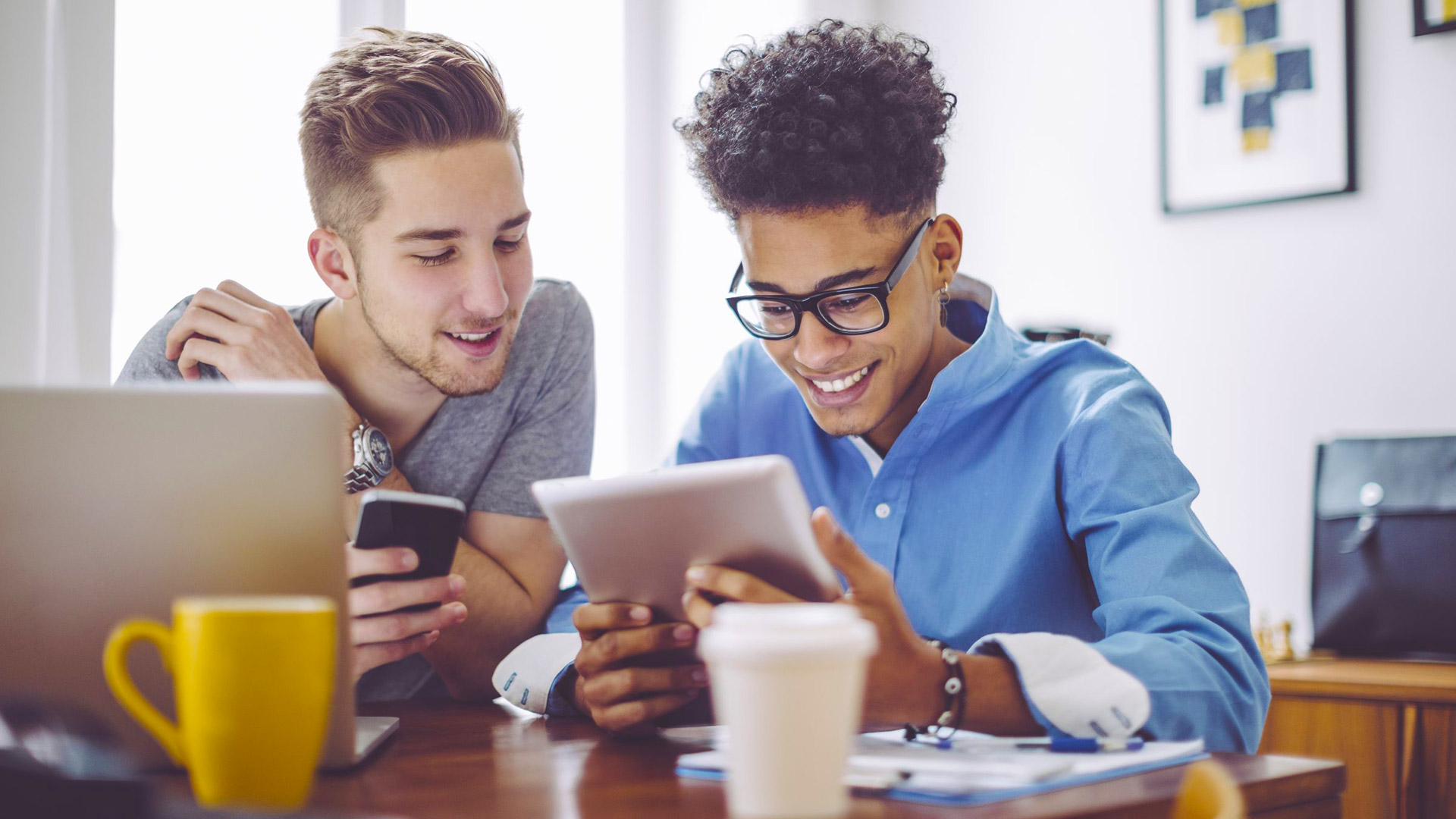 2 young men looking at tablet and phone