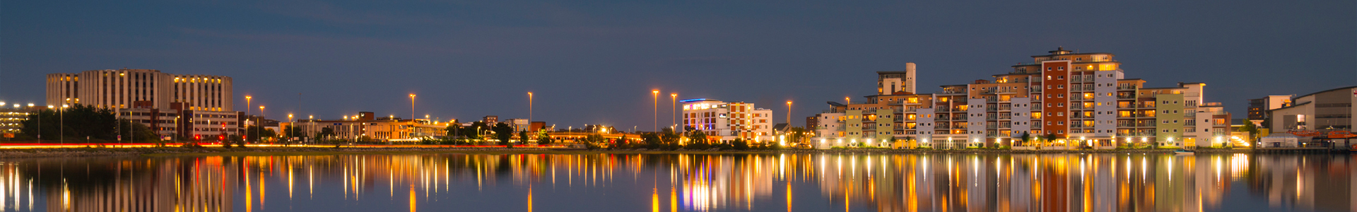 Reflections are cast on the still harbour waters with the bright lights of Poole's backwater developments