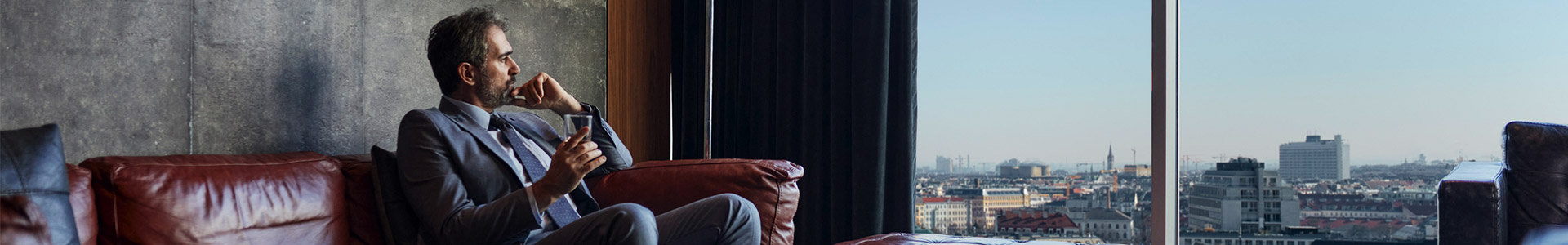 Business man sitting on sofa relaxing looking out over city