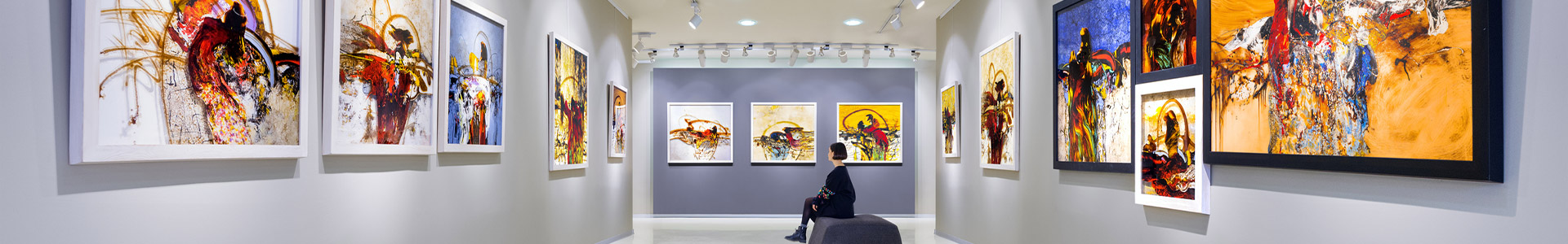 Female sat in art gallery looking at the art hanging on the walls