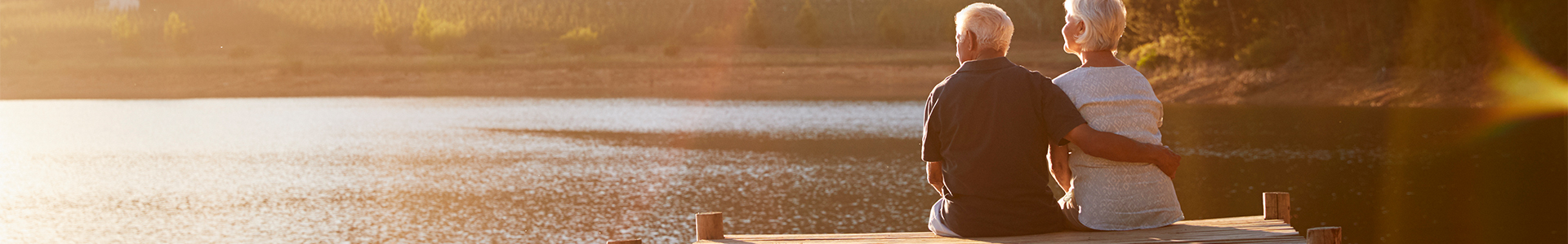 Older couple sitting on a dock looking out over a lake