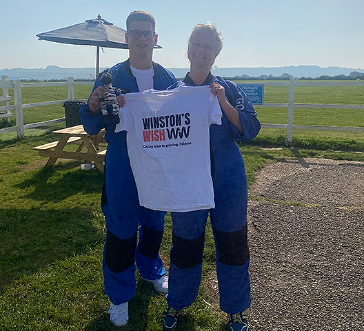 Skydivers holding a Winston’s Wish charity t-shirt along with a Zebbie toy