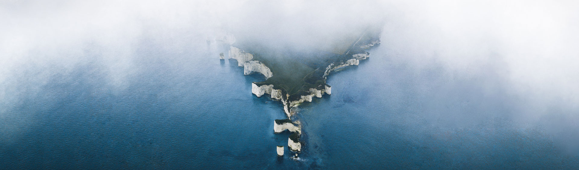 Birdseye view of white cliffs jutting out into the ocean behind the haze