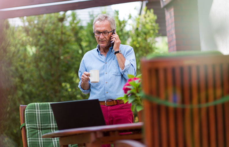 Middle-aged man on the phone drinking coffee outdoors