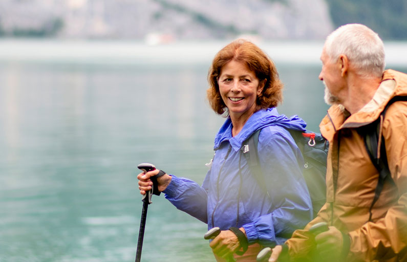 Happy middle-aged couple hiking by the water