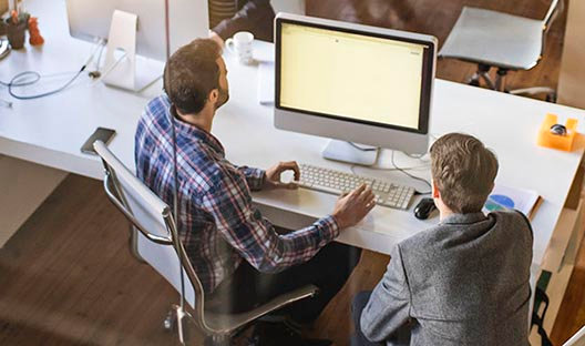 Two men working on a computer at a desk