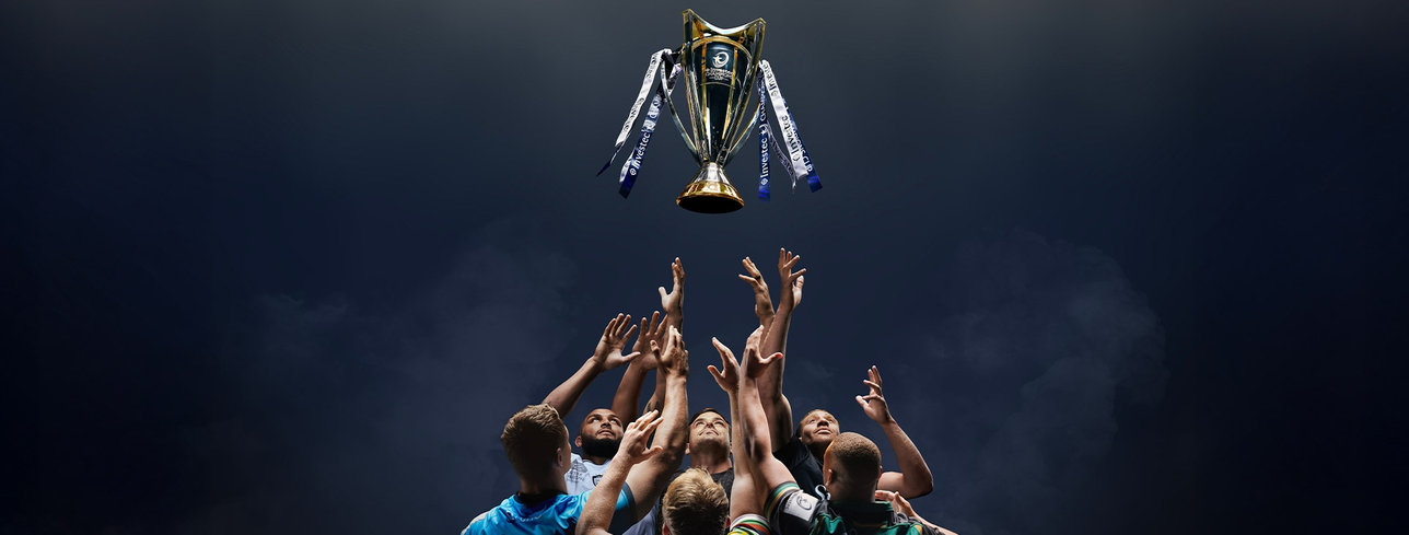 Rugby players throwing the Investec Champions Cup into the air.