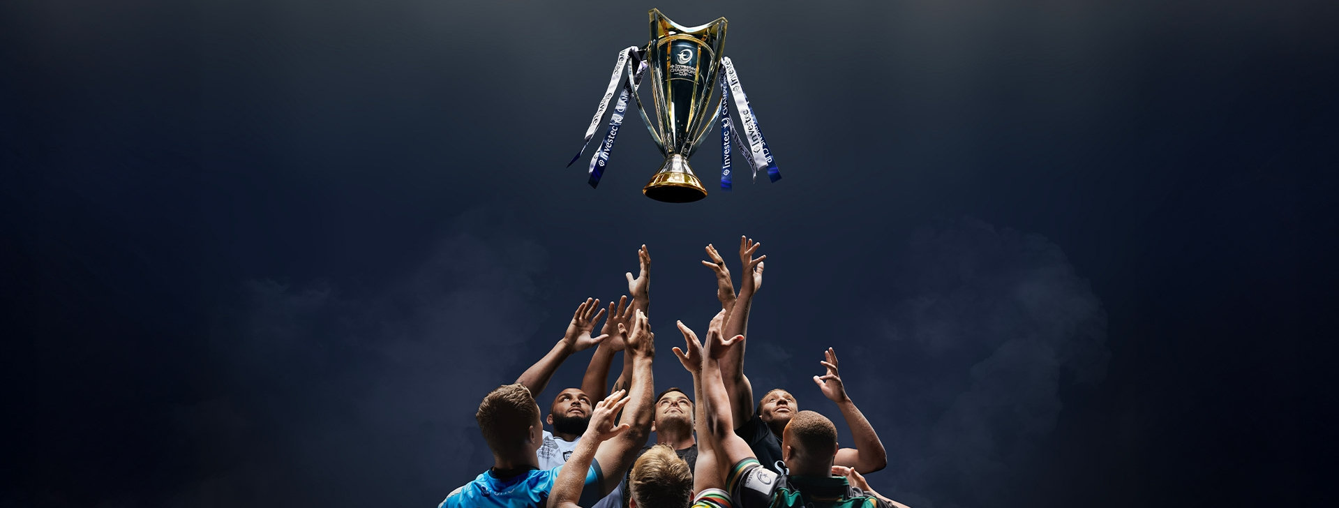 Rugby players throwing the Investec Champions Cup into the air.